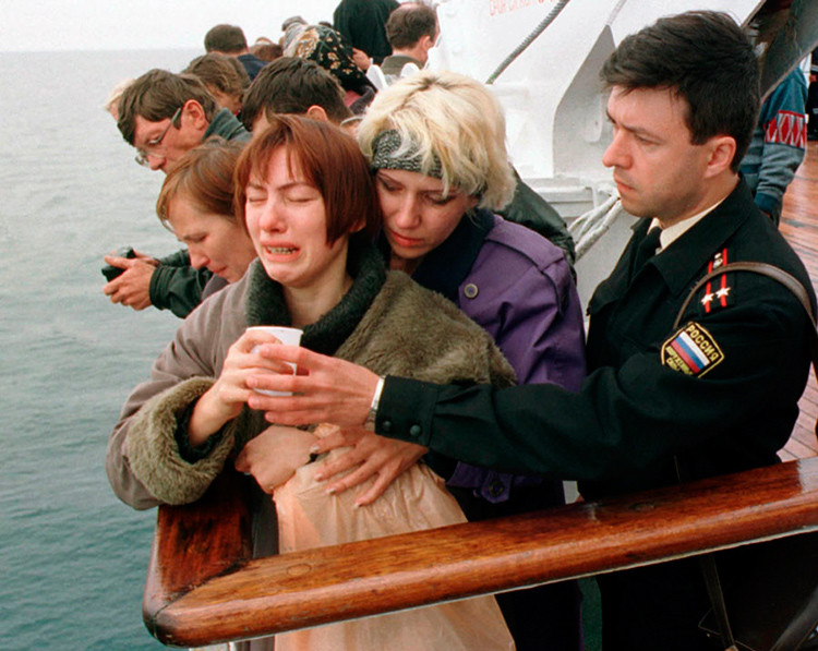 Un oficial de marina ofrece una bebida a una familiar de un marinero fallecido en la tragedia del Kursk durante una ceremonia celebrada en el  lugar donde se hundió el submarino.