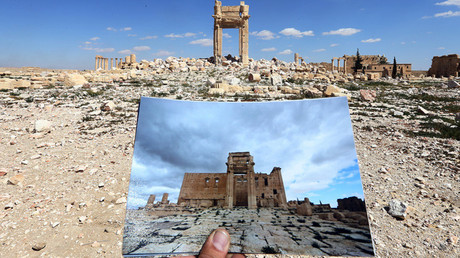 Esta vista general tomada el 31 de marzo de 2016 muestra al fotógrafo sosteniendo una foto del templo de Bel tomada el 14 de marzo de 2014.