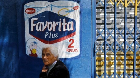 Una mujer jubilada pasa al lado de un cartel publicitario de papel higiénico