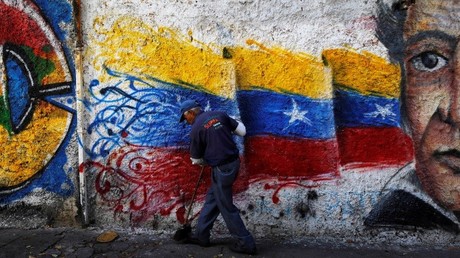 Un barrendero limpia la calle junto a una pintura con los colores de la bandera venezolana, Caracas, Venezuela, el 8 de junio de 2016.