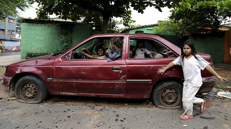 Niños juegan con un auto abandonado en las calles de Asunción, Paraguay