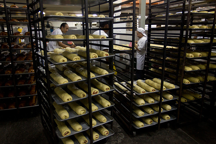 Trabajadores llevan bandejas de pan de jamón en una pastelería, Caracas, Venezuela, el 31 de diciembre de 2011.