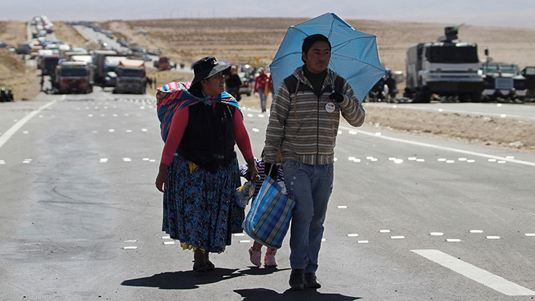Los pasajeros de un autobús caminan por la carretera bloqueada por los mineros en Panduro