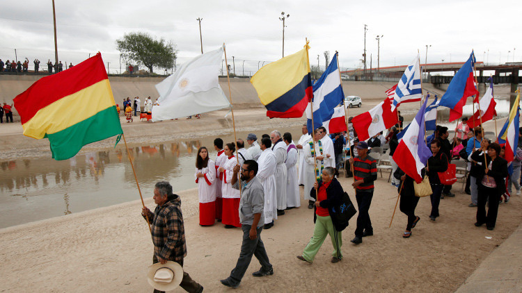 Personas con banderas en el lado mexicano de la valla fronteriza entre Ciudad Juárez (México) y El Paso (EE.UU.), durante una manifestación en apoyo de los migrantes