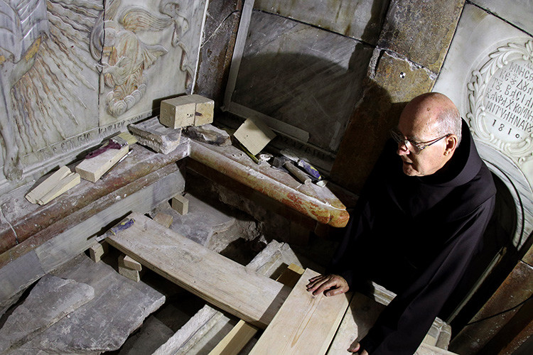 Un fraile franciscano observa la tumba expuesta en la que se cree que fue sepultado el cuerpo de Jesús. Allí un equipo griego de preservación realiza trabajos de conservación. Jerusalén, Israel, 28 de octubre de 2016.