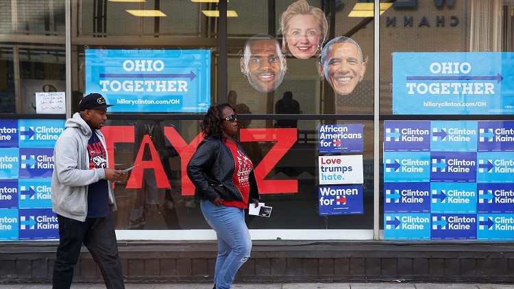Varias personas pasan junto a un establecimiento que distribuye entradas para un concierto de apoyo a la candidata demócrata a la presidencia de EE.UU., Hillary Clinton, en Cleveland, Ohio, EE.UU., el 29 de octubre de 2016.