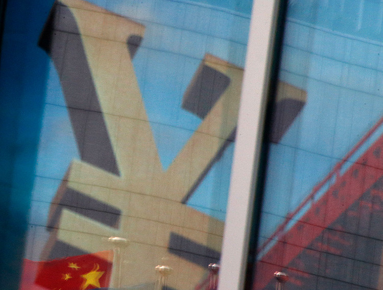 La bandera nacional de China se refleja en un anuncio que lleva el símbolo del yuan chino en una sucursal de un banco comercial en un distrito de negocios en Pekín, capital de China, el 21 de enero de 2016