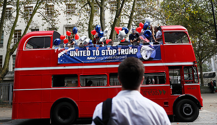 Un activista ata banderas estadounidenses a un autobús con la leyenda 'Stop Trump' antes de viajar por Londres para instar a los estadounidenses residentes en la capital del Reino Unido a registrarse y votar en las presidenciales, el 21 de septiembre de 2016.
