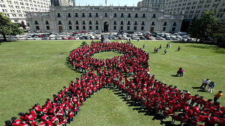 Centenares de niños chilenos vestidos de rojo forman el símbolo de la campaña contra el sida frente al Palacio de La Moneda