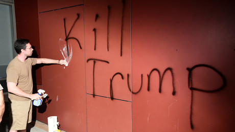 Un hombre trata de remover un grafiti que reza 'Kill Trump' (Mata a Trump), durante una protesta en Oakland (California, EE.UU.), el 9 de noviembre de 2016.