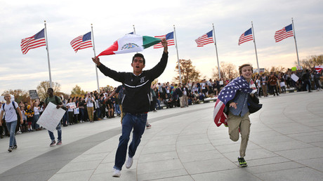 Un estudiante corre con una bandera mexicana junto a otro que porta una bandera estadounidense en una protesta contra Donald Trump en Washington. 