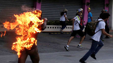 Hombre que fue incendiado por personas que lo acusaron de robar durante una manifestación contra el Presidente de Venezuela, Nicolas Maduro, corre en medio de partidarios de la oposición en Caracas, Venezuela, el 20 de mayo de 2017.