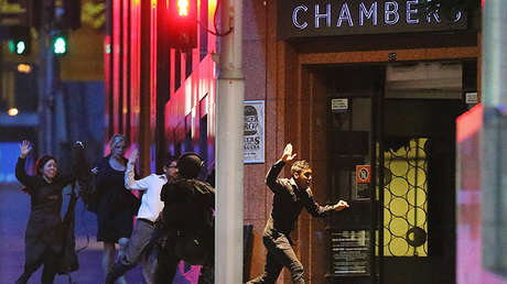 Un grupo de personas huye con las manos arriba del café Lindt durante una toma de rehenes en Sídney, Australia, el 16 de diciembre de 2014.